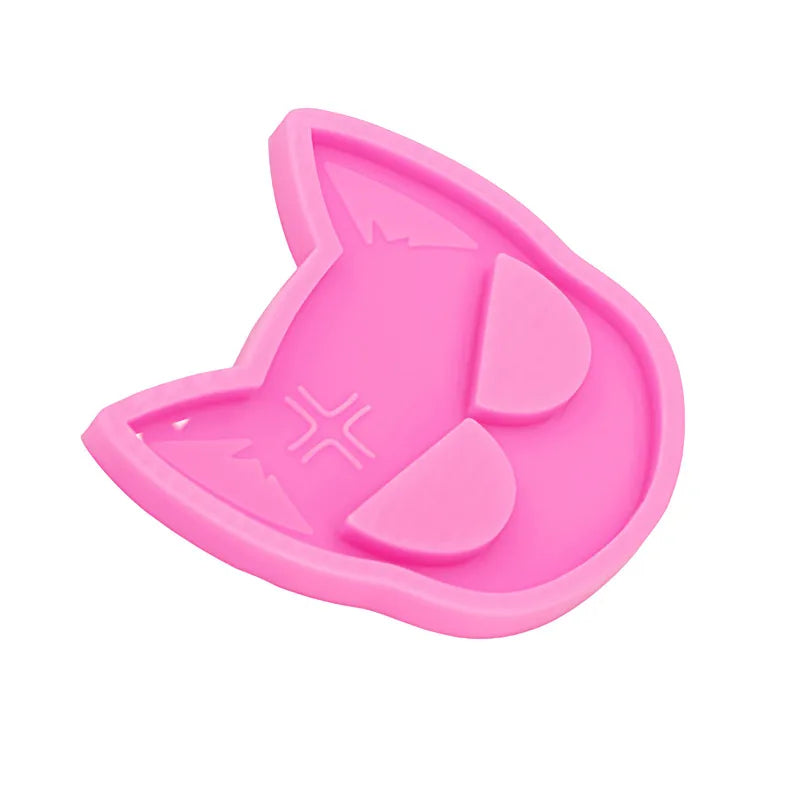 A pink silicone mold shaped like a cat's head for DIY keychains and craft projects.