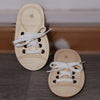 A pair of light wooden lacing shoes for a toy, showing the laces and star details.