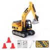 A yellow mini RC excavator model with black details and tracks, shown next to several red traffic cones.