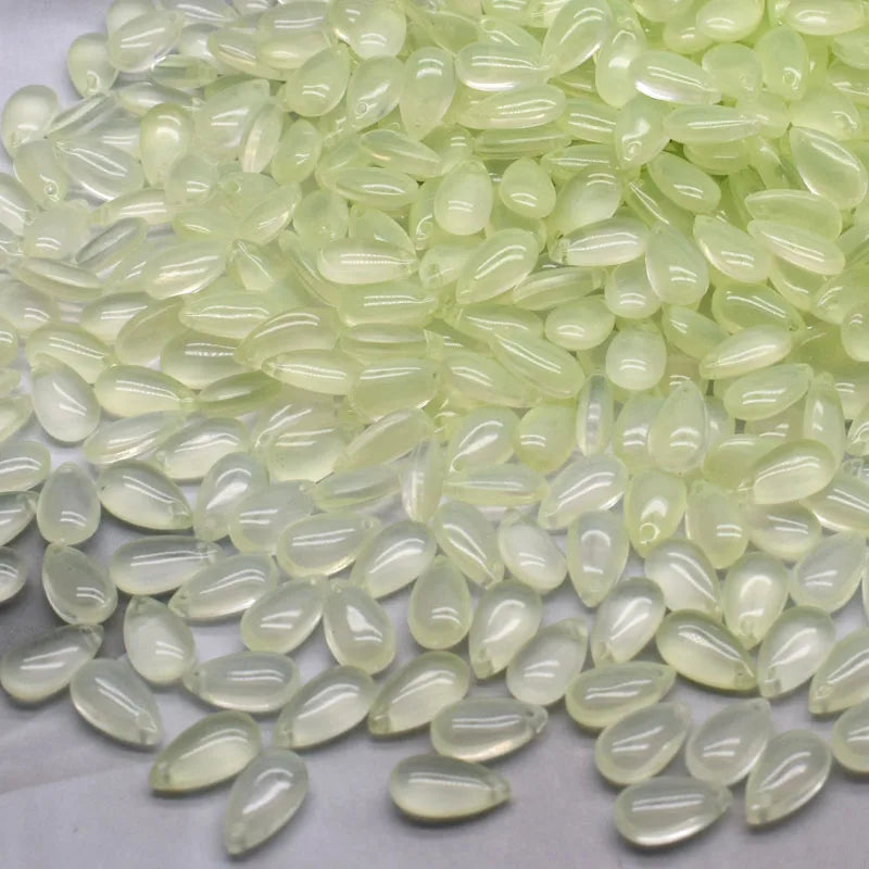 A pile of translucent pale green water drop Czech glass beads for jewelry making.