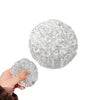 A hand is holding a clear, spherical stress ball made of numerous small beads.