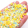 A hand holds a pile of yellow and pastel colored polymer clay slices for DIY crafts