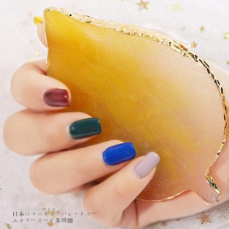 A hand holds a luxury resin nail art palette with gold trim, displaying various colored resin pieces.