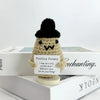 A handwoven crochet ornament shaped like a potato with a black pom-pom hat sitting on a book.