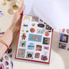 A hand holds an open book filled with retro aesthetic stickers for DIY crafting projects.