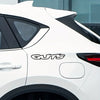 A white car with a black roof spoiler and the GUTS letter vinyl sticker on the side.
