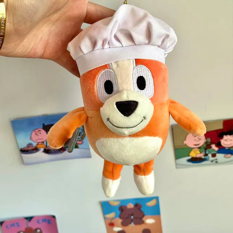 An orange and white plush doll resembling a dog wearing a white chef's hat.