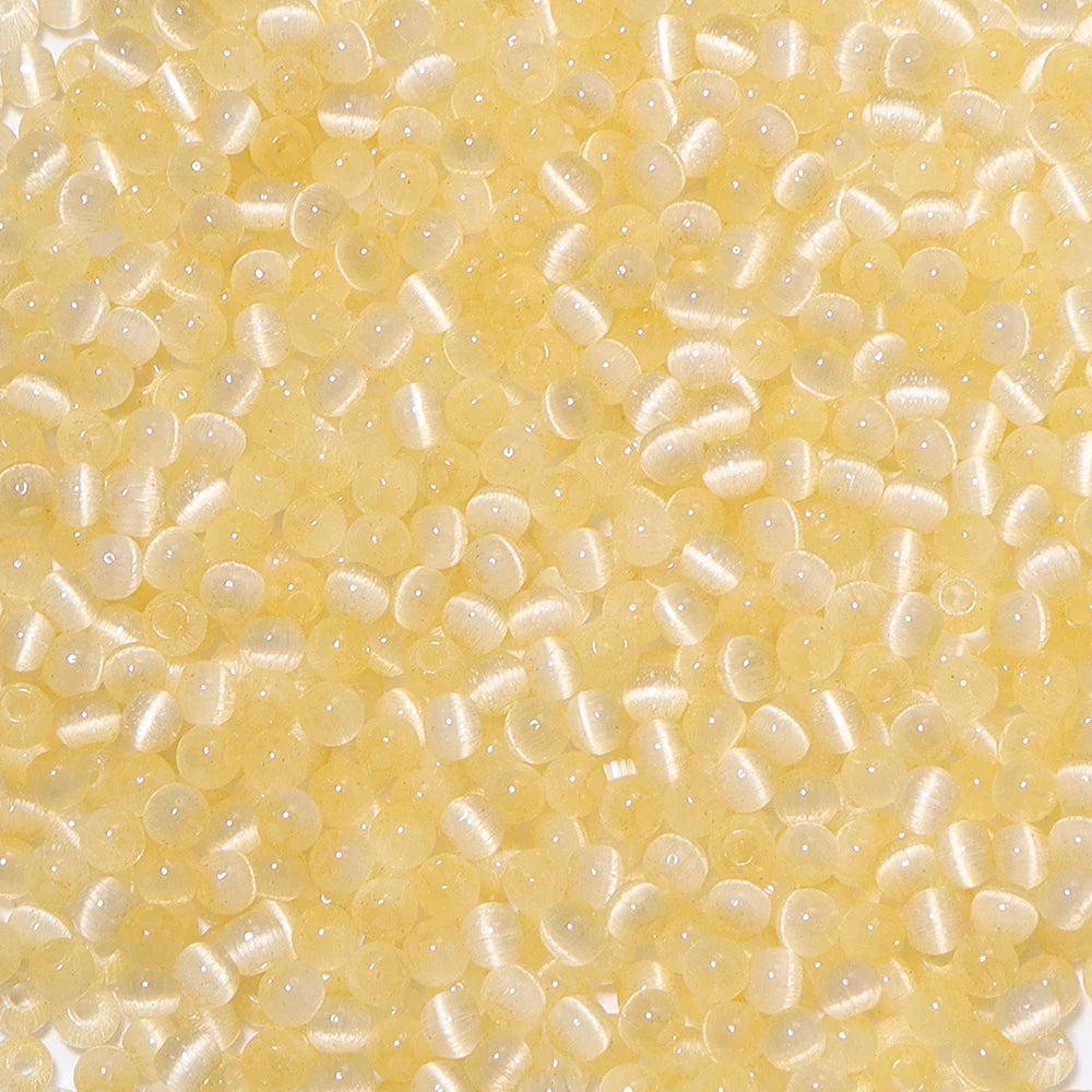 A close-up view of a colorful mix of 4mm cat eye glass beads for jewelry making.