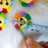 Handmade crochet sunflower decorative smile orb resting on white fur with a ruler.