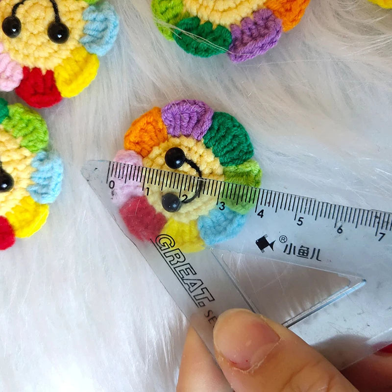 Handmade crochet sunflower decorative smile orb resting on white fur with a ruler.