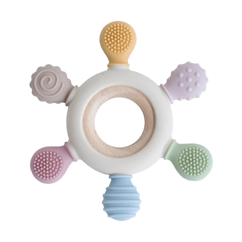 A silicone baby teether shaped like a rudder with a wooden ring and various colored silicone tips.