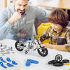 A child and adult are assembling a detailed metal building motorcycle construction kit on a white table.