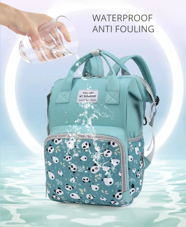A teal mommy backpack is shown with water splashing, demonstrating waterproof anti-fouling features.