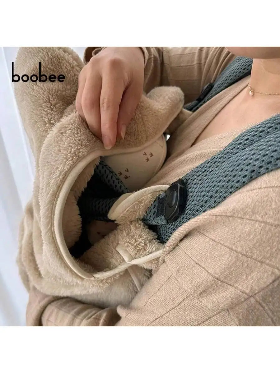 A person is holding a beige baby windproof cape blanket with a dinosaur design.