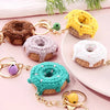 A collection of colorful crochet donut keychains on a pink surface.