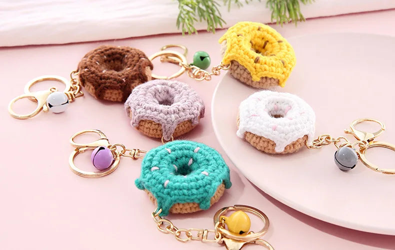 A collection of colorful crochet donut keychains on a pink surface.
