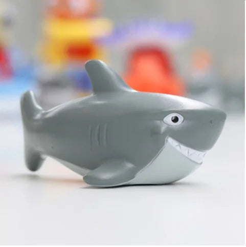 A gray rubber toy dolphin floating on a white surface.