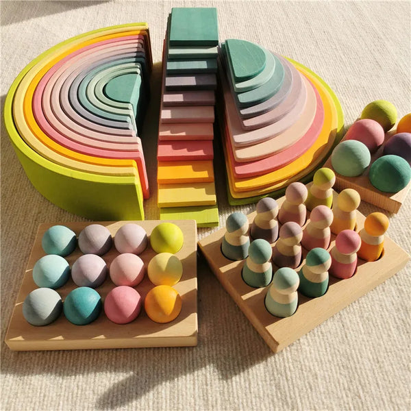 Un juego de bloques de madera pastel apilados en un arcoíris y varias pilas en una tabla de madera.