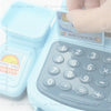 A light blue interactive cash register toy with a clear lid and keypad is shown being held by a hand.