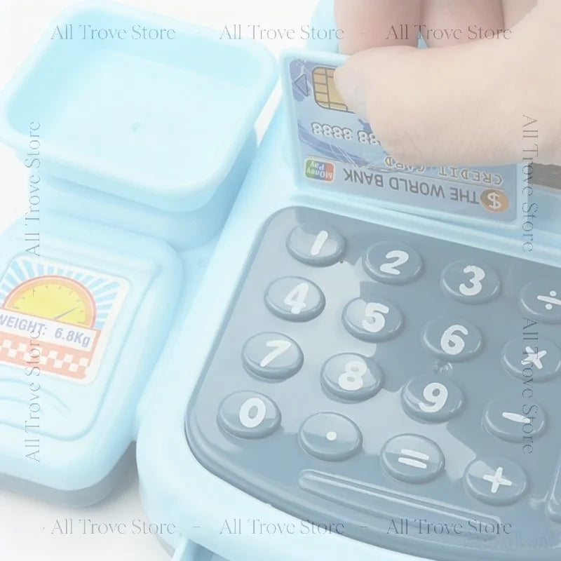 A light blue interactive cash register toy with a clear lid and keypad is shown being held by a hand.