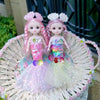 A pink mermaid doll with sparkly hair and a colorful dress is displayed in a woven basket.