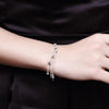 A close-up of a woman's wrist wearing an elegant sterling silver snake chain bracelet.