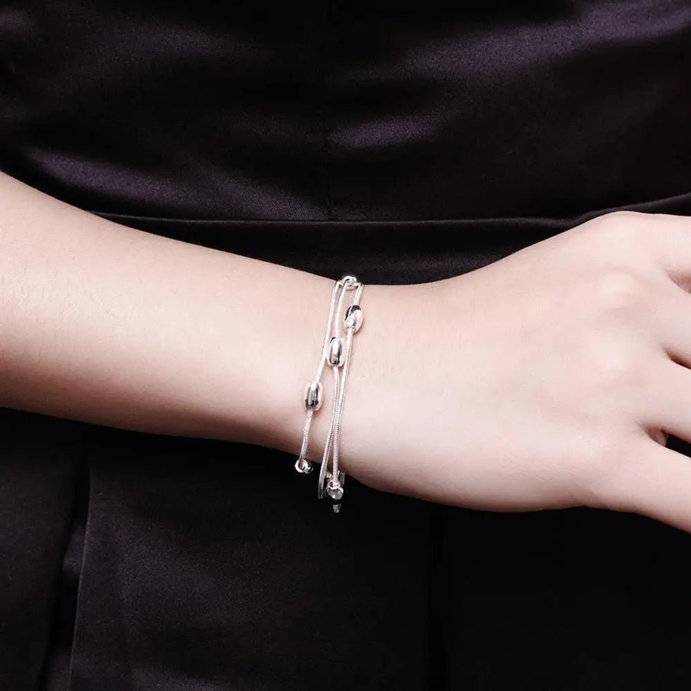 A close-up of a woman's wrist wearing an elegant sterling silver snake chain bracelet.