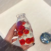A hand holds a clear glass bottle filled with red and white squishy stress balls for sensory relaxation.