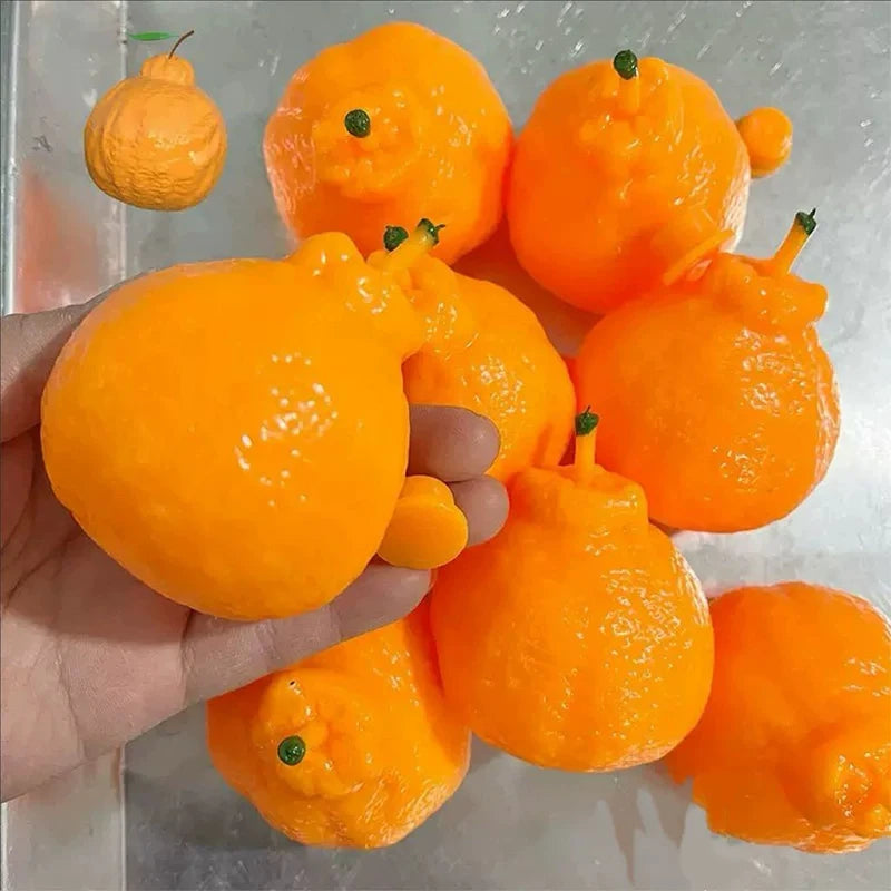 A hand holds several bright orange, squishy stress relief toys or fidget blocks.