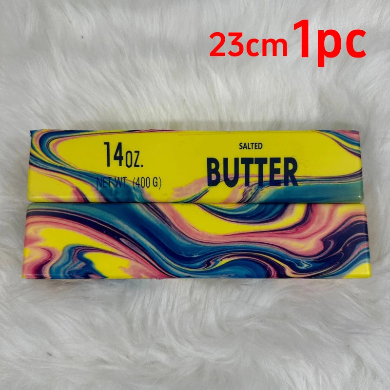 A rectangular bar of salted butter with colorful marbled patterns is displayed on a white fluffy surface.