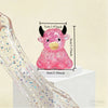 A pink glitter highland cow squishy stress relief fidget toy is shown with its dimensions.