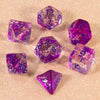 A collection of glitter purple polyhedral dice including D4, D6, D8, D10, D12, and D20 resting on a sparkling surface.