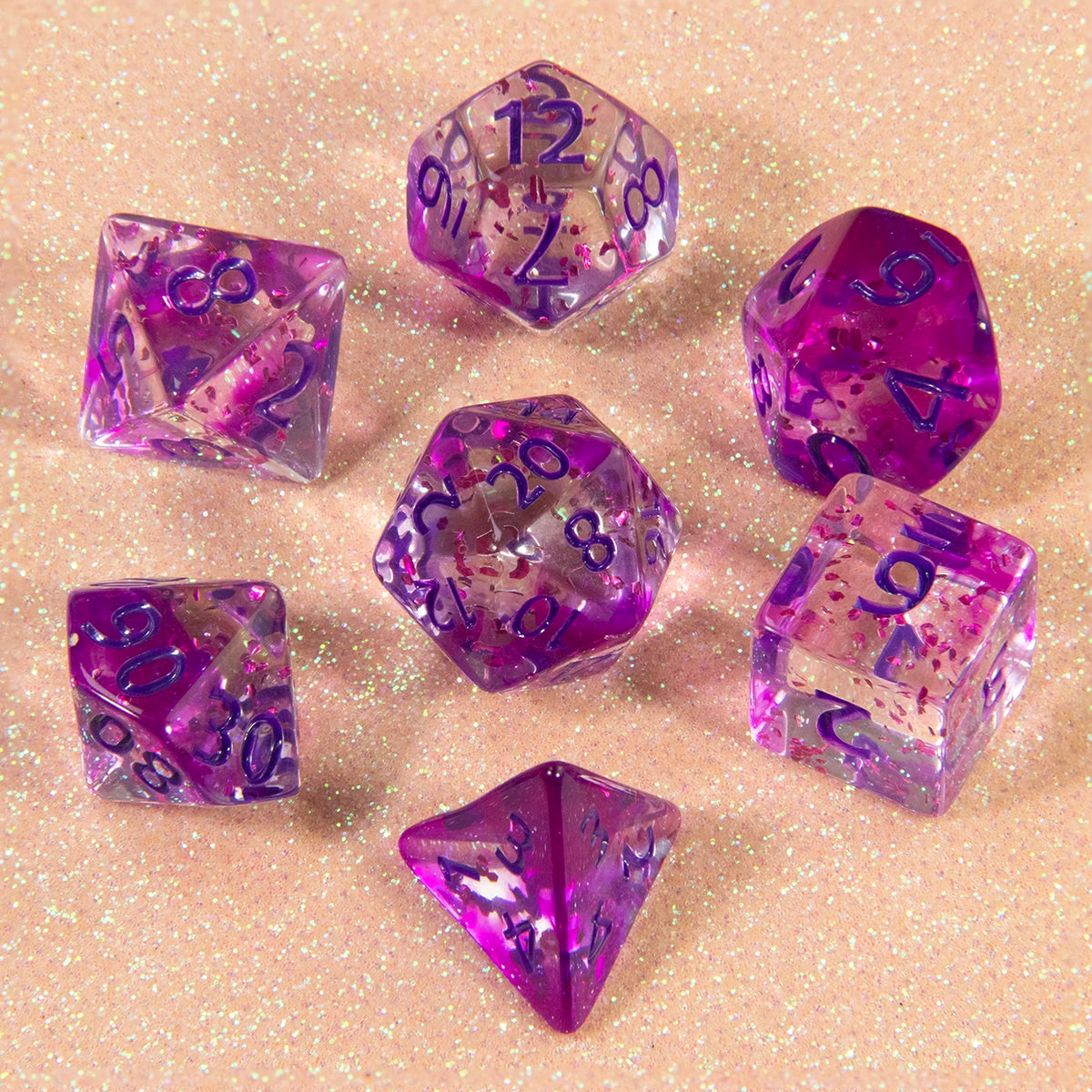 A collection of glitter purple polyhedral dice including D4, D6, D8, D10, D12, and D20 resting on a sparkling surface.