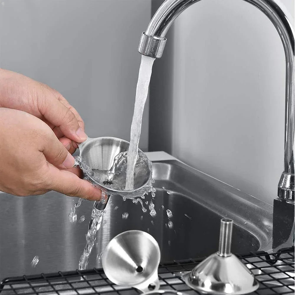 A hand pours water from a stainless steel funnel into a kitchen sink, demonstrating the use of a stainless steel funnel set.