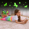 A young girl lies on a pink rug wearing a glow-in-the-dark mermaid tail blanket while looking at a book.