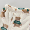 A set of cream-colored fleece jacket and pants featuring brown teddy bear cartoon prints with green accents.
