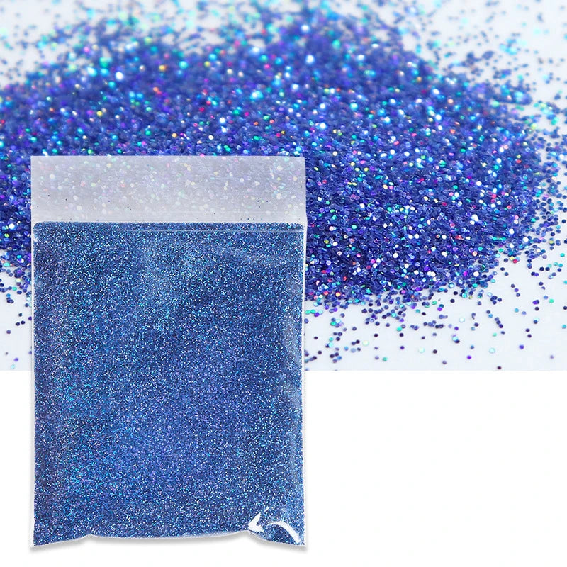 A small plastic bag filled with vibrant blue holographic glitter powder scattered on a white surface.
