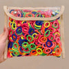 A multi-pack of colorful nylon hair ties in various bright colors like pink, green, blue, and orange, packaged in a clear pla