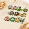 A set of cute green turtle enamel pins featuring various designs and text on a beige sweater.