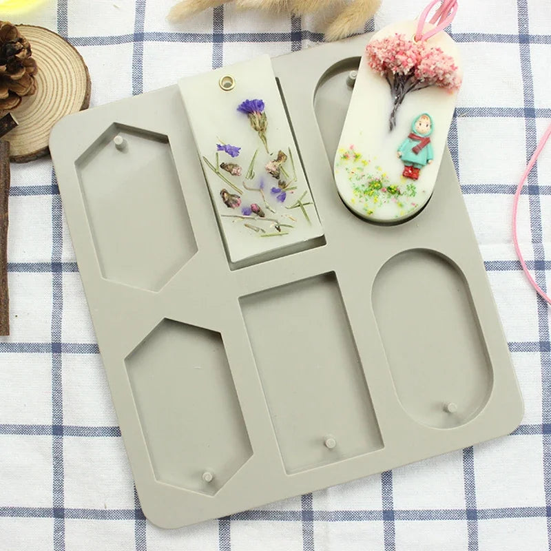 A gray silicone mold tray with multiple hexagonal cavities, featuring a pink floral soap design.