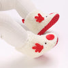 A pair of white baby first walker shoes shaped like a reindeer with red accents.