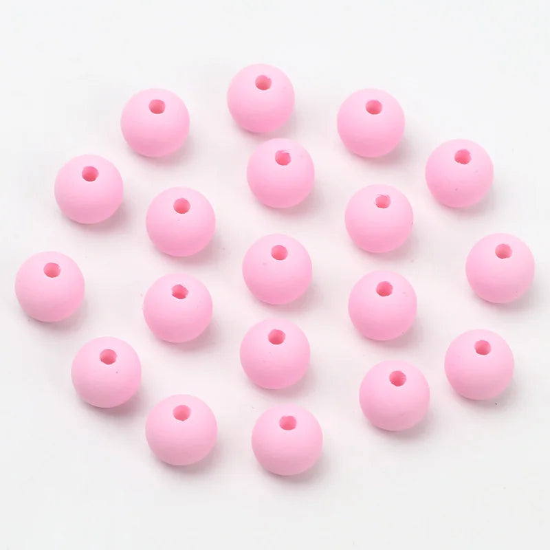 A collection of pink matte acrylic beads scattered on a white background.