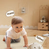 A baby is interacting with an electronic crawler toy while learning to call themselves Mom and Dad.