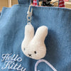 A white Miffy cartoon rabbit keychain pendant hanging from a silver split ring on a blue fabric bag.