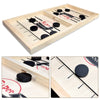 A wooden catapult tabletop hockey game board with black and white pieces and a winner marker.