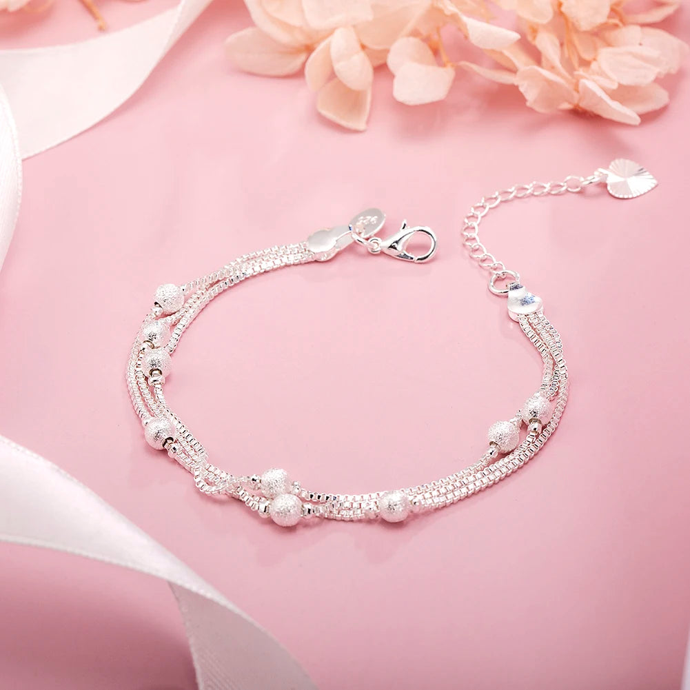 Elegant sterling silver snake chain bracelet for women displayed on a pink background