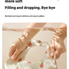 A hand is holding a white baby bandana bib with small pink strawberry embroidery.
