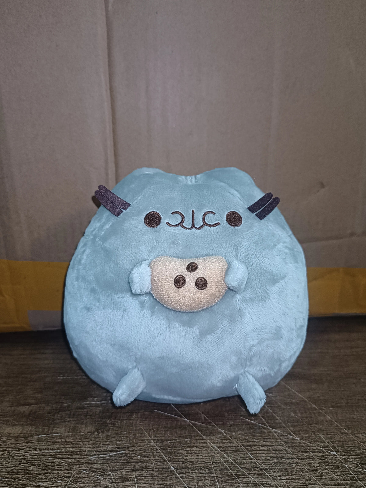 A light blue anime-inspired plush cat doll with brown horns and a cute facial expression.