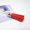 A silver-tipped orange velvet tassel is shown resting on a purple card with white floral designs.