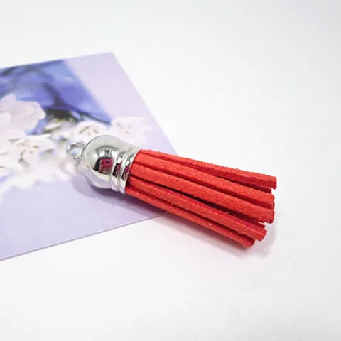 A silver-tipped orange velvet tassel is shown resting on a purple card with white floral designs.